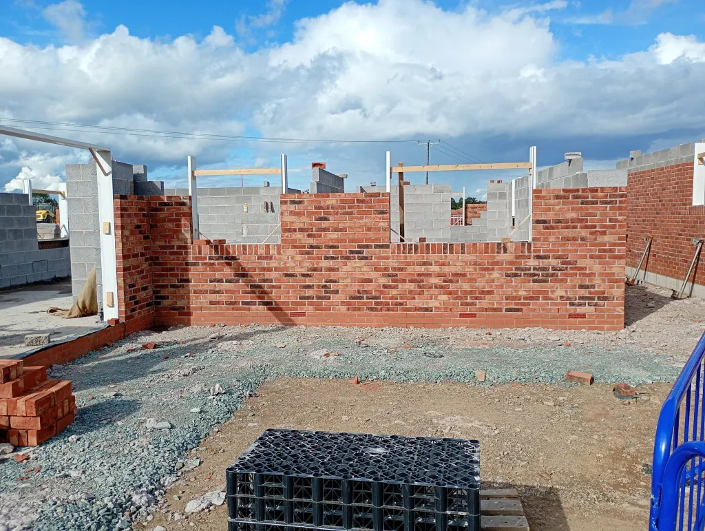 Bungalow walls a metre above ground in red facing brick with a grey blockwork inner leaf and door frames set in