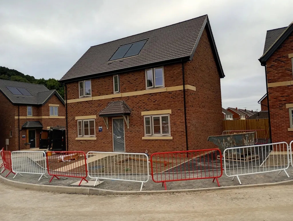 New detached house in multi red brick with buff stone band and sills, roof solar panels and a canopy over the door